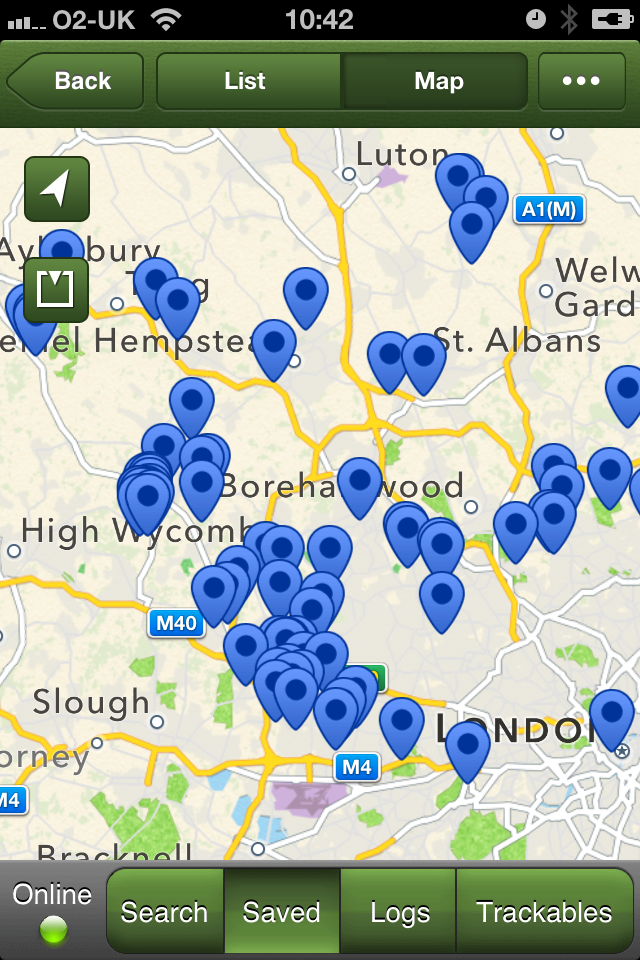 This iPhone screenshot shows a map covered with over 70 geocache markers showing the locations of puzzle caches that have been solved but not yet collected.