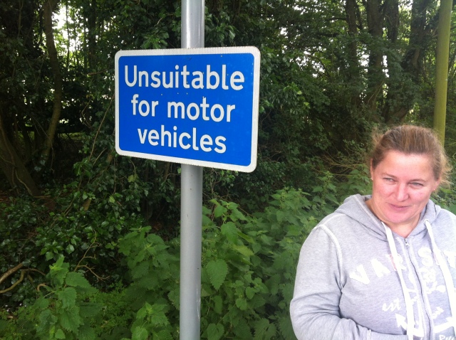 Sharlene is picture standing on a country lane next to a sign that states "Unsuitable for Motor Vehicles"